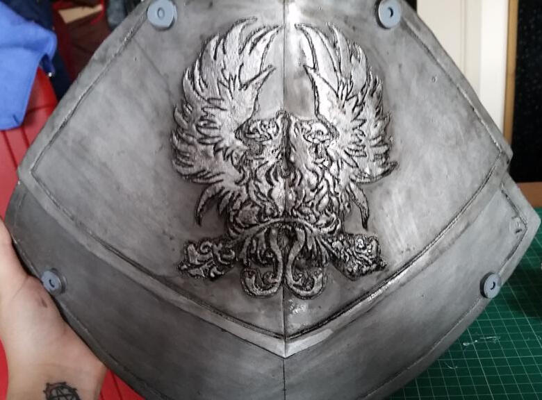 A close up of the Grey Warden armour breastplate with the double Griffon crest embossed on the front