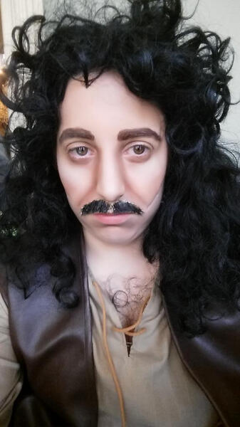 A cosplayer dressed as Inigo Montoya from the Princess Bride, complete with heavy makeup to form a more masculine face, scars, and a moustache.