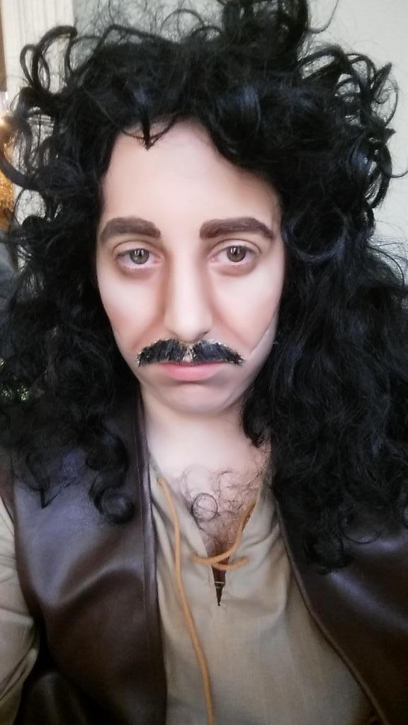 A cosplayer dressed as Inigo Montoya from the Princess Bride, complete with heavy makeup to form a more masculine face, scars, and a moustache.